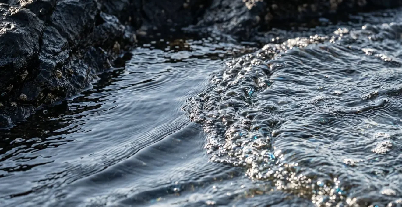 Vue aérienne d'une petite baie rocheuse montrant les courants de retour visibles dans l'eau turquoise